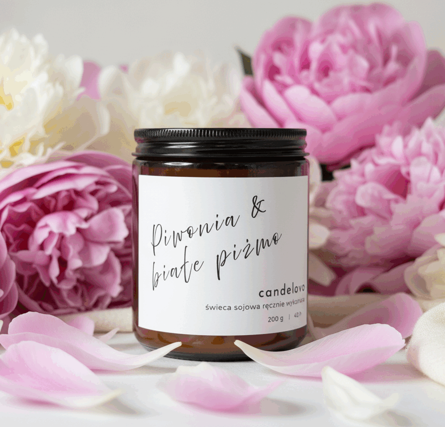 Świeca sojowa Piwonia & Białe Piżmo Candelovo – naturalna świeca w brązowym słoiczku otoczona płatkami i kwiatami piwonii w pastelowych odcieniach.